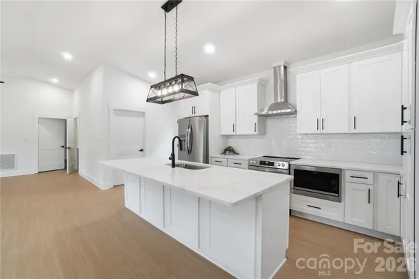 a kitchen with stainless steel appliances a sink a stove a refrigerator and white cabinets