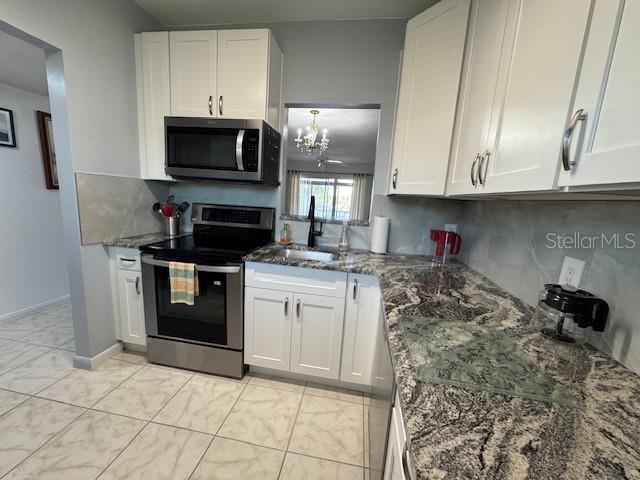 11485 Oakhurst Road, Unit 319 Largo, FL 33774 - Photo 22 of 63 a kitchen with granite countertop a stove a sink and a microwave