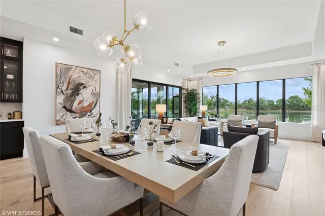 a dining room with kitchen island furniture a chandelier and a view of kitchen