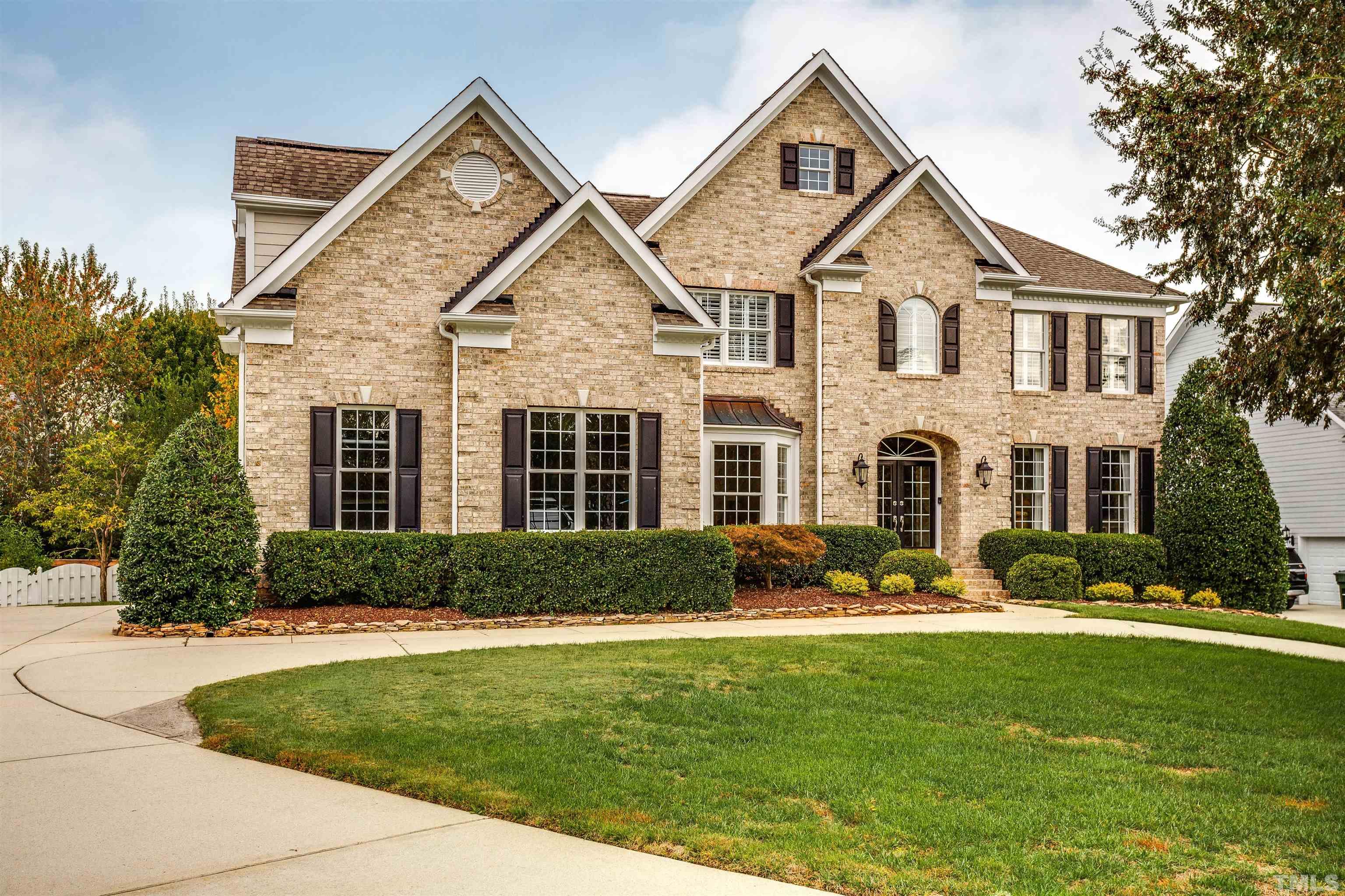 a front view of a house with a yard and trees