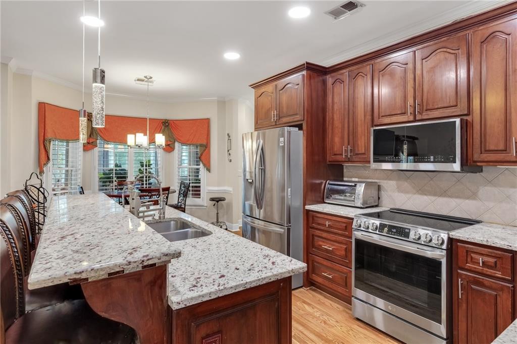 211 Graymist Path Southwest Loganville, GA 30052 - Photo 15 of 65 a kitchen with stainless steel appliances granite countertop wooden cabinets a stove top oven a sink and dishwasher