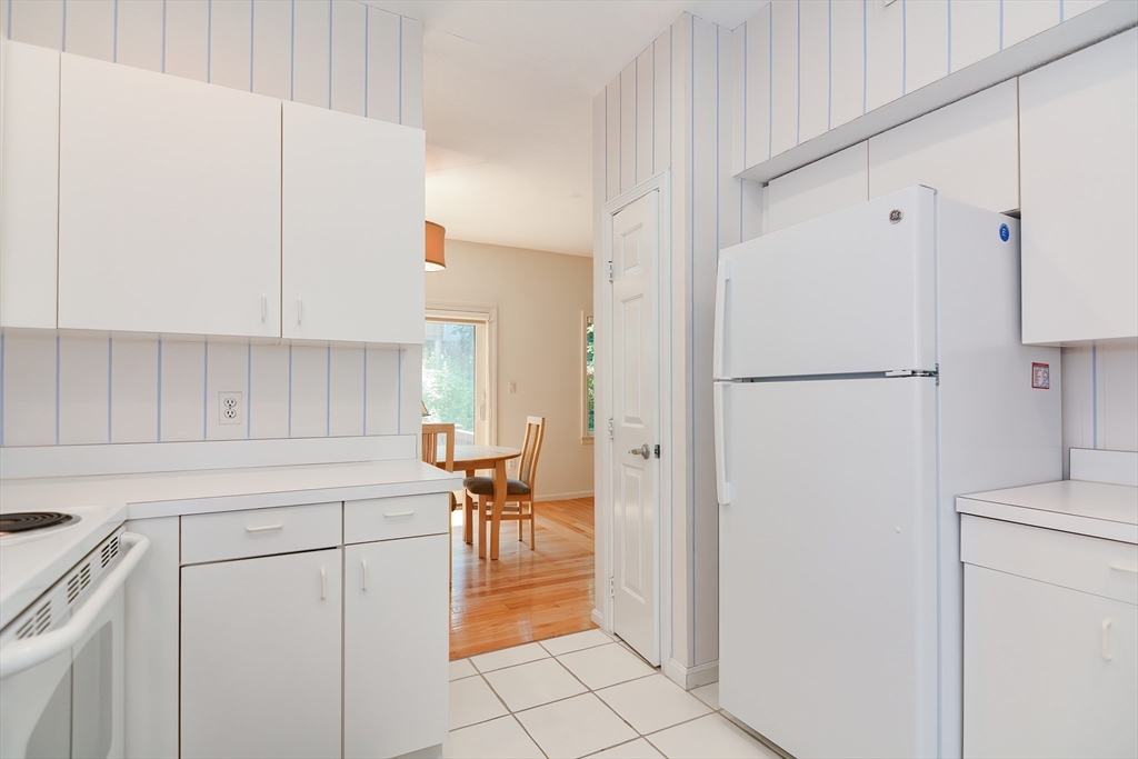 327 Bishops Forest Drive, Unit 327 Waltham, MA 02452 - Photo 11 of 38 a kitchen with a refrigerator a stove and white cabinets