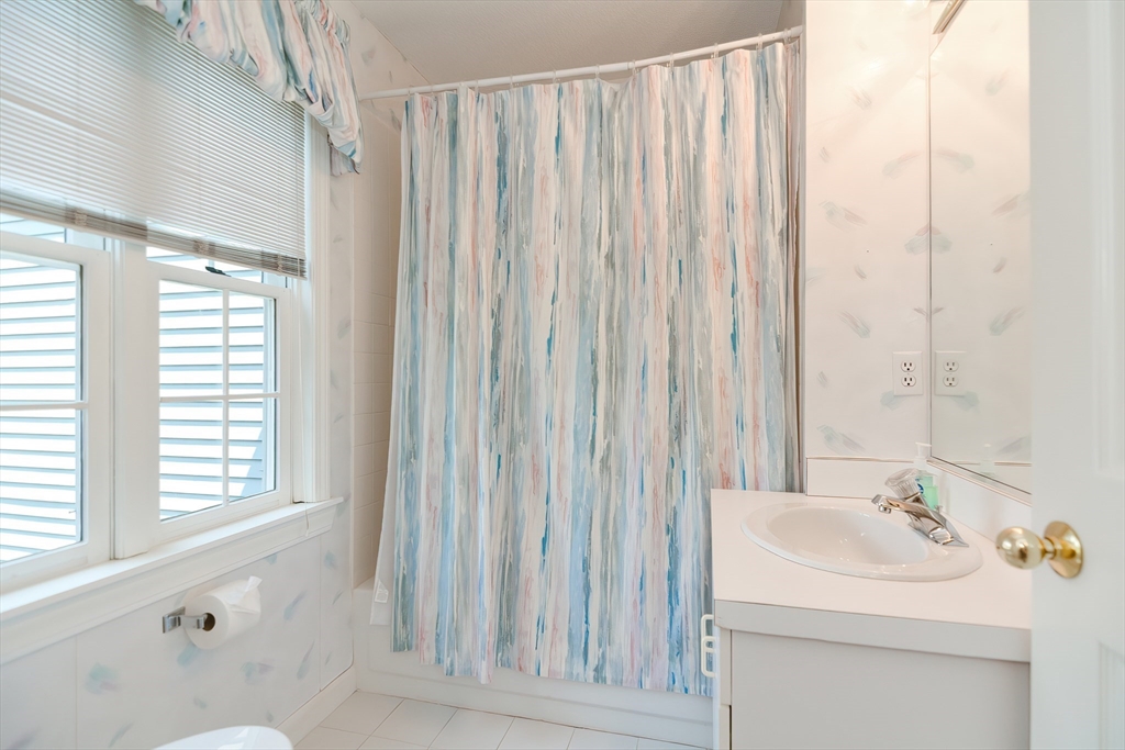 327 Bishops Forest Drive, Unit 327 Waltham, MA 02452 - Photo 28 of 38 a bathroom with a sink a mirror and a shower curtain
