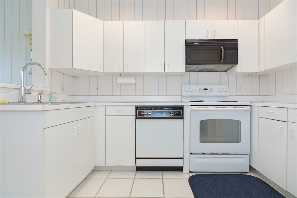 327 Bishops Forest Drive, Unit 327 Waltham, MA 02452 - Photo 10 of 38 a kitchen with white cabinets and stainless steel appliances