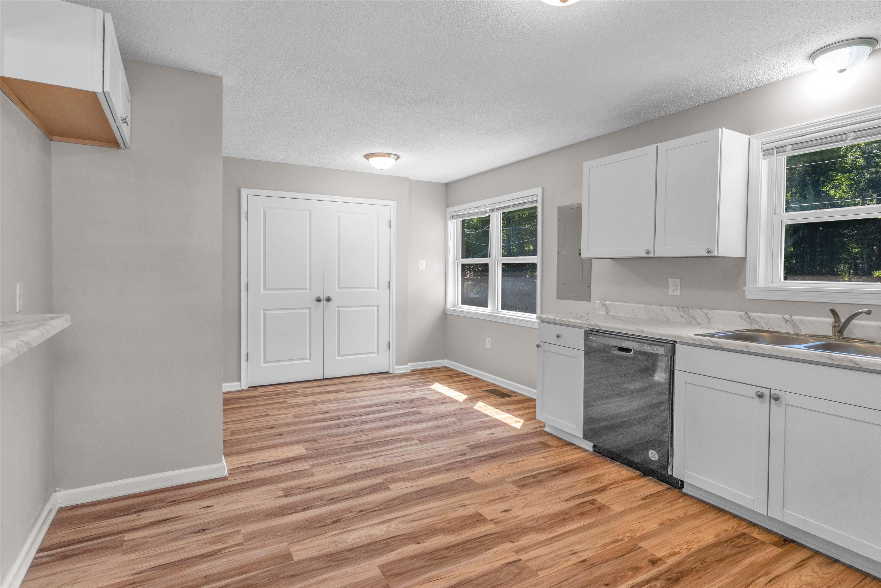 185 Henry Road Somerville, TN 38068 - Photo 10 of 21 Wood-finish flooring, white cabinetry, stainless-steel dishwasher, dual windows, and ceiling-mounted light fixtures