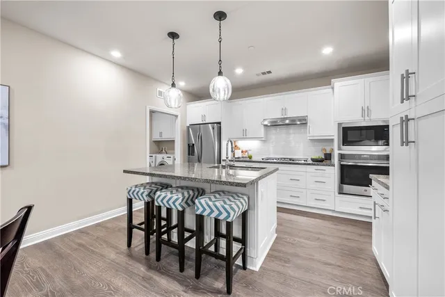 a kitchen with stainless steel appliances kitchen island granite countertop a table chairs and a refrigerator