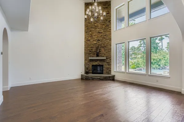 an empty room with wooden floor fire place and windows