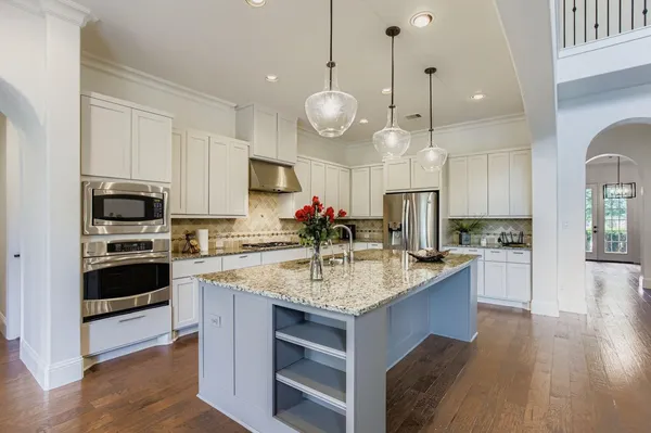 a kitchen with stainless steel appliances kitchen island granite countertop a stove a sink and a wooden floor