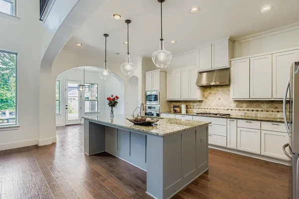 a kitchen with stainless steel appliances granite countertop a sink a stove and a wooden floor