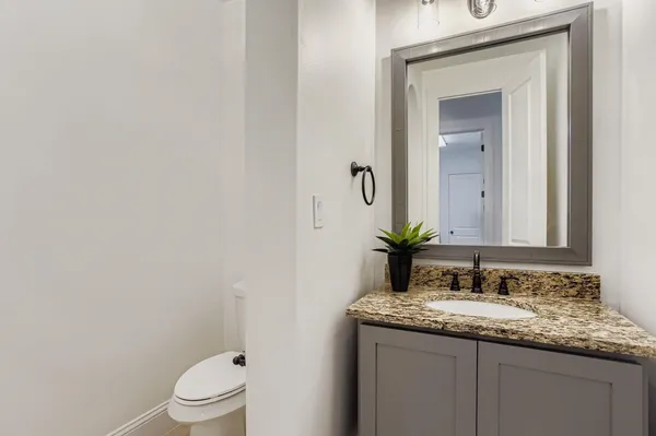 a bathroom with a granite countertop sink toilet and mirror