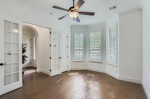 a view of empty room with wooden floor and fan
