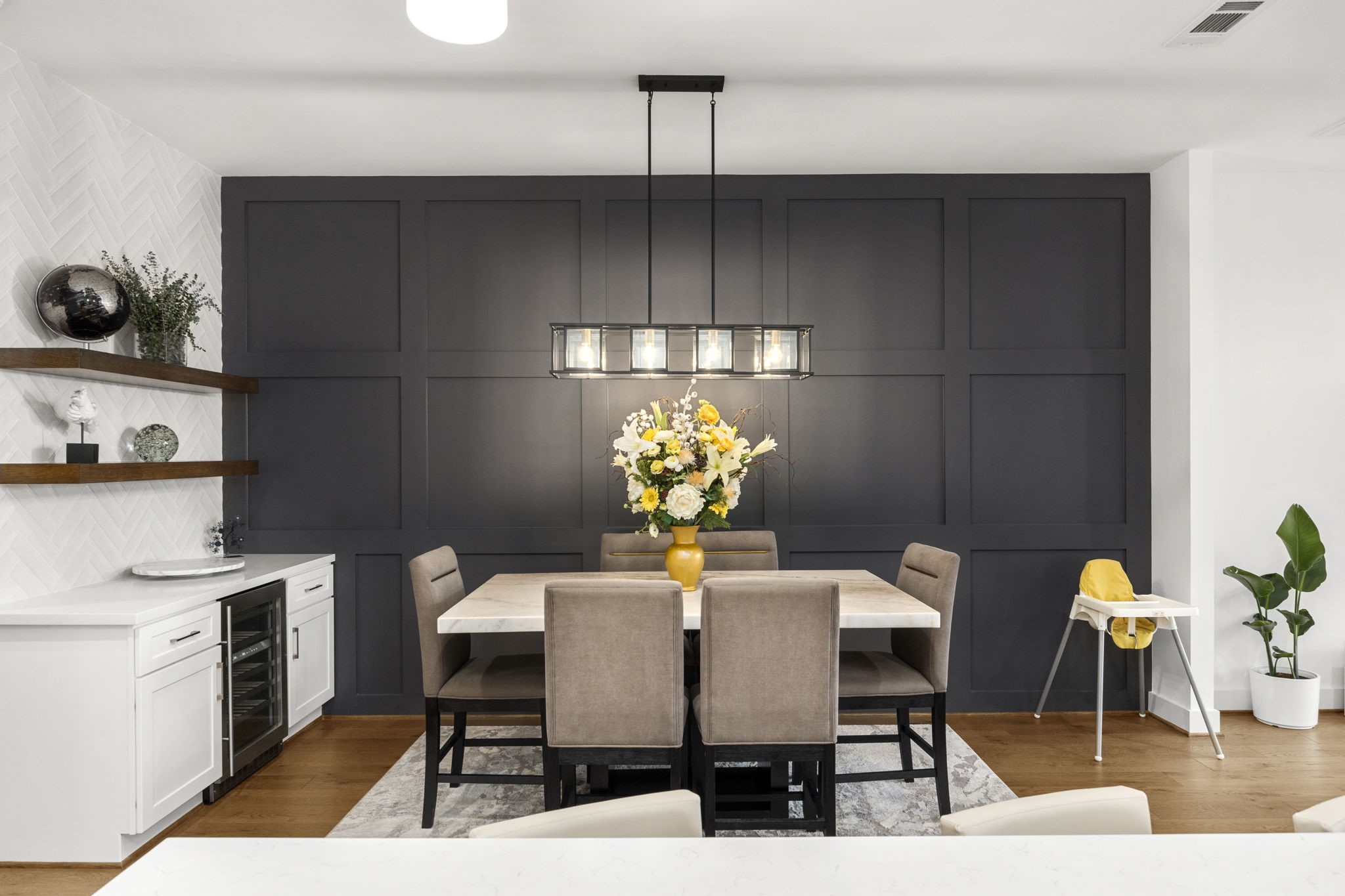 2411 Hazard Street Houston, TX 77019 - Photo 19 of 46 This elegant dining room features a striking accent wall with sophisticated paneling that adds depth and texture to the space. A modern chandelier illuminates the marble-topped dining table, creating a perfect setting for both intimate dinners and larger gatherings. The built-in bar area with floating shelves and a wine cooler provides additional storage and style.