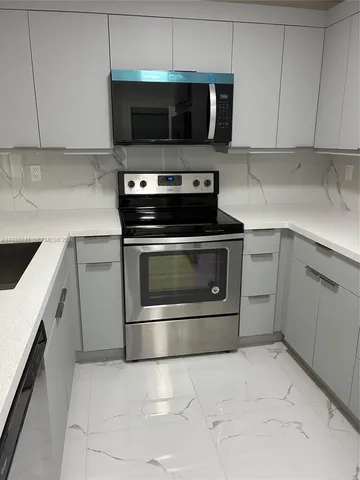 a kitchen with granite countertop a sink stainless steel appliances and cabinets