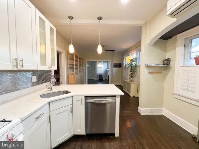 a kitchen with a sink dishwasher and white cabinets with wooden floor