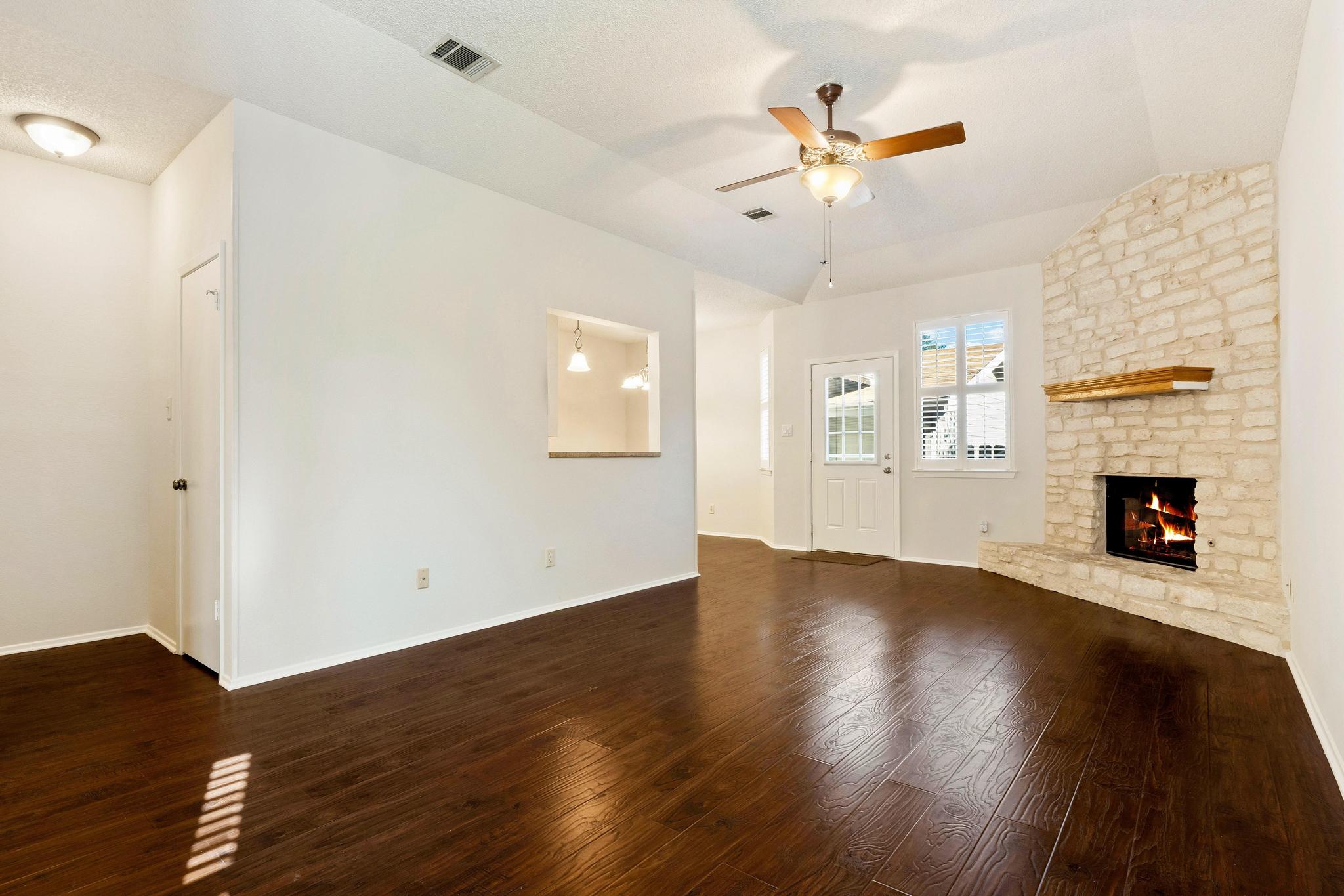 6501 Brush Country Road, Unit 109 Austin, TX 78749 - Photo 3 of 26 a view of an empty room with wooden floor and a fireplace