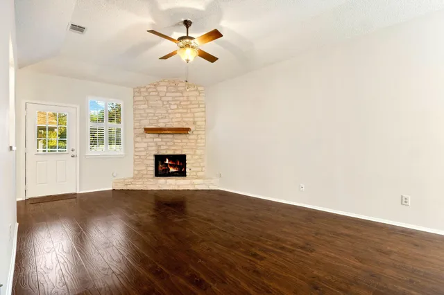 an empty room with wooden floor fireplace and window