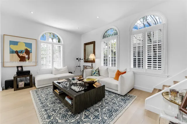 a living room with furniture couches and a dining table with wooden floor