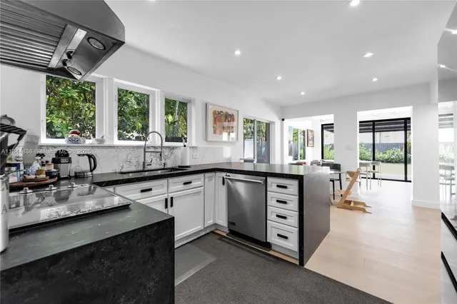 a kitchen with stainless steel appliances granite countertop a sink a stove a refrigerator cabinets and a dining table