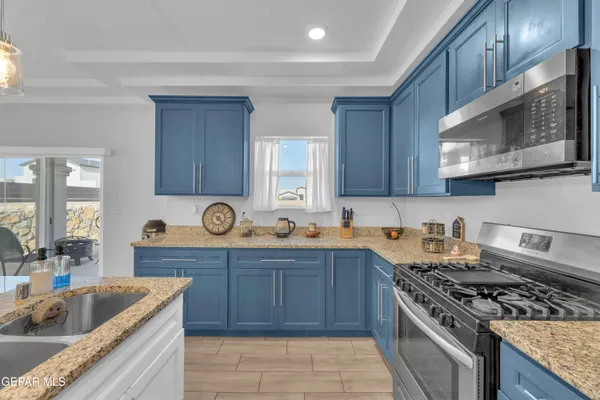 a kitchen with granite countertop a sink a stove and wooden cabinets