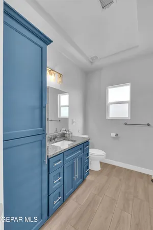 a bathroom with a granite countertop sink toilet and mirror