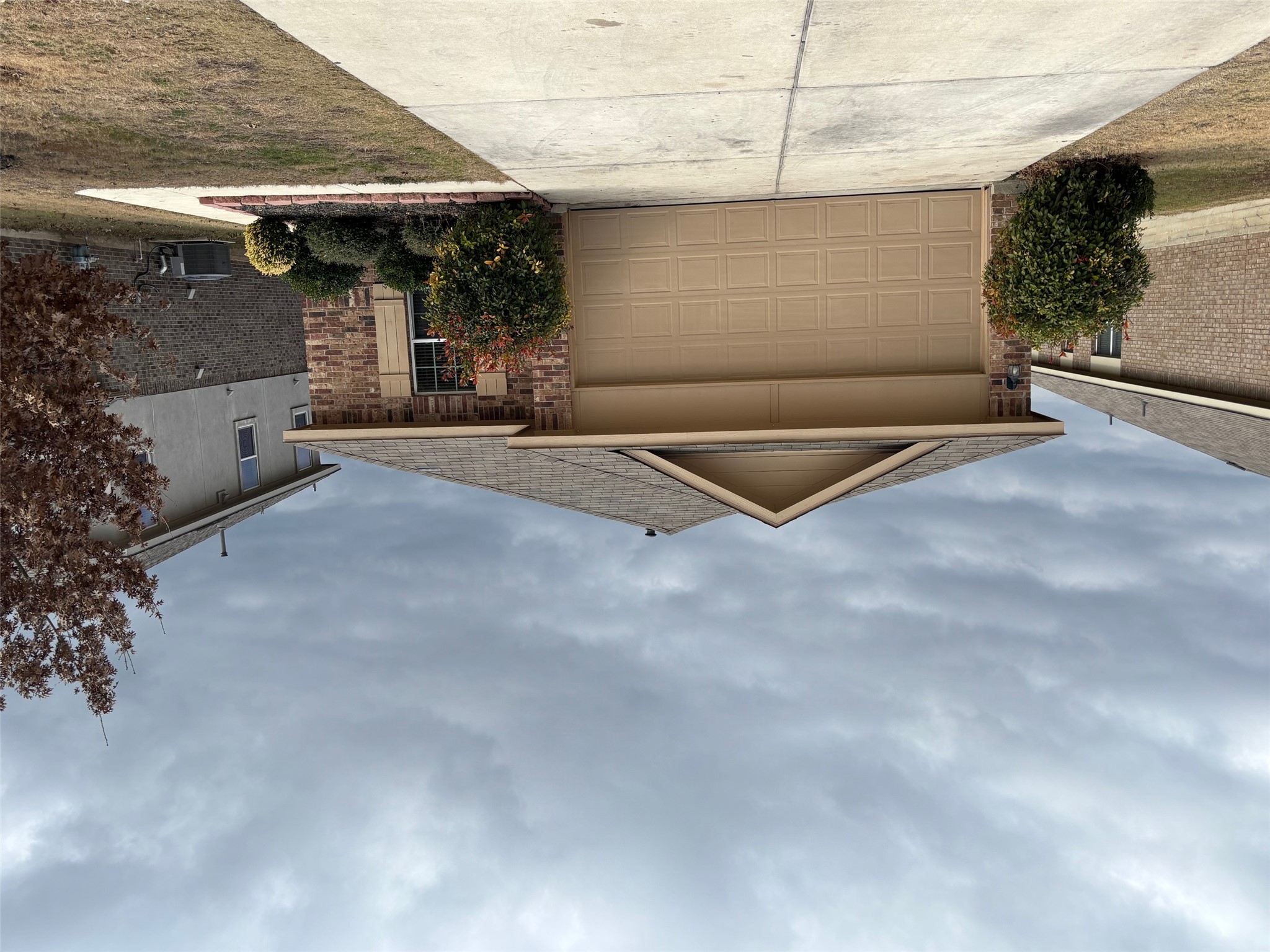 Ranch-style home featuring concrete driveway, a garage, brick siding, and roof with shingles