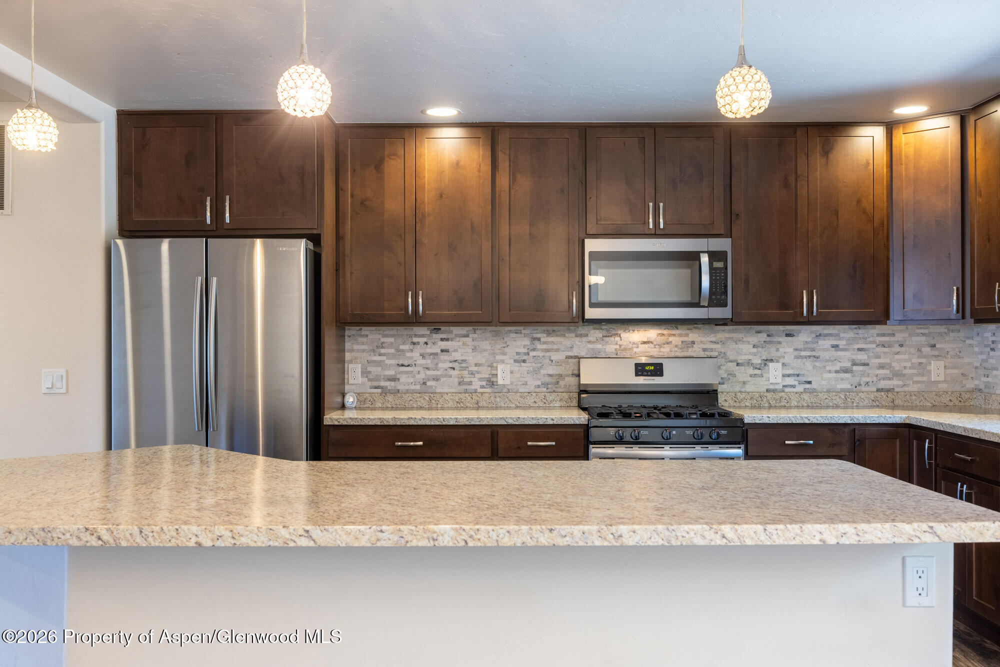 2016 Ballard Avenue Silt, CO 81652 - Photo 3 of 23 a kitchen with stainless steel appliances granite countertop a refrigerator a stove top oven and a sink with wooden cabinets