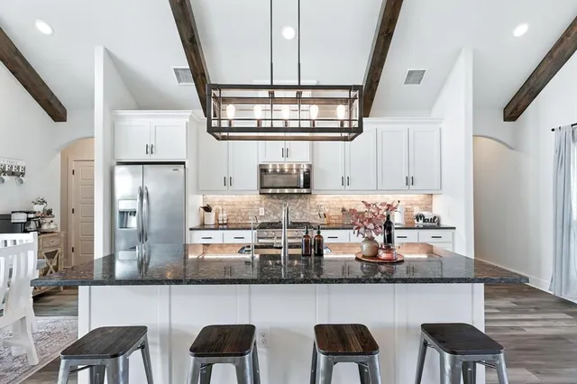 a kitchen with stainless steel appliances granite countertop a table chairs in it and wooden floors