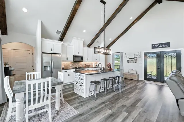 a kitchen with stainless steel appliances a dining table chairs stove and a sink