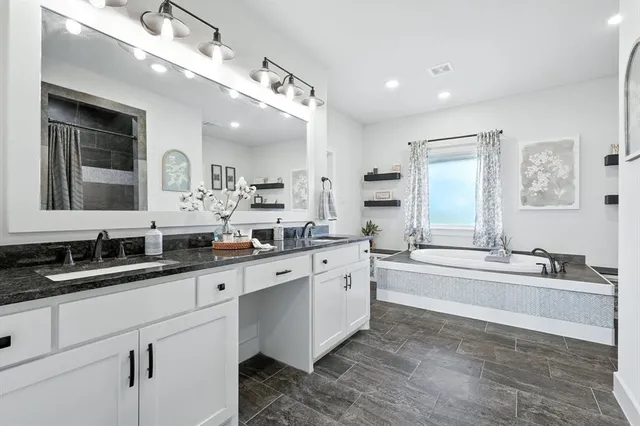 a large white bathroom with a large tub sink and double vanity