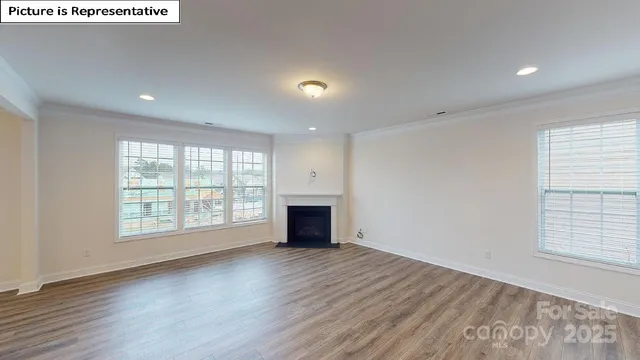 an empty room with wooden floor fireplace and windows