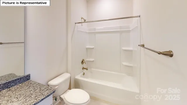 a bathroom with a granite countertop bathtub shower sink vanity and toilet