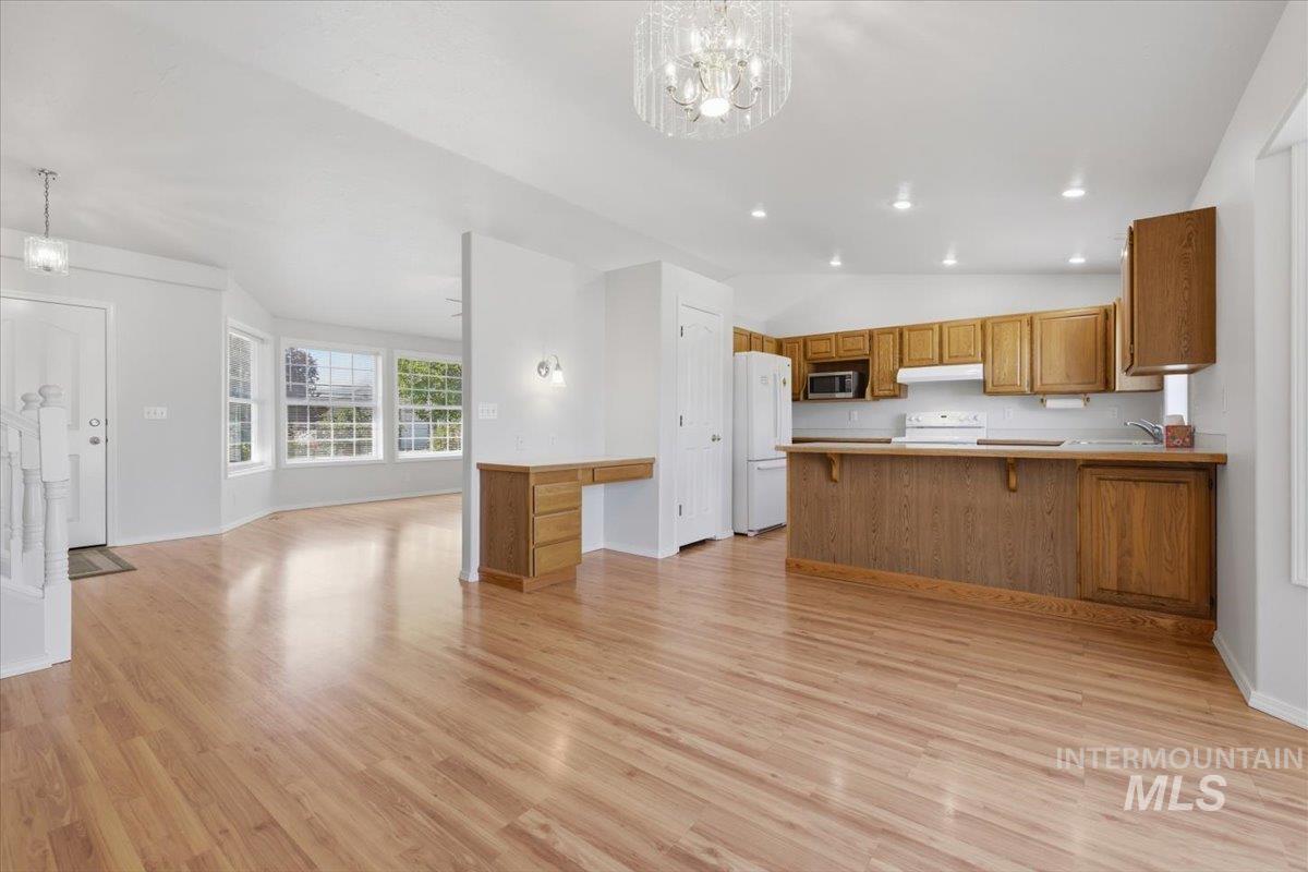 1128 West State Street Meridian, ID 83642 - Photo 14 of 50 Open-concept living space featuring wood-finish flooring, a kitchen with light wood cabinetry, a breakfast bar, and white appliances