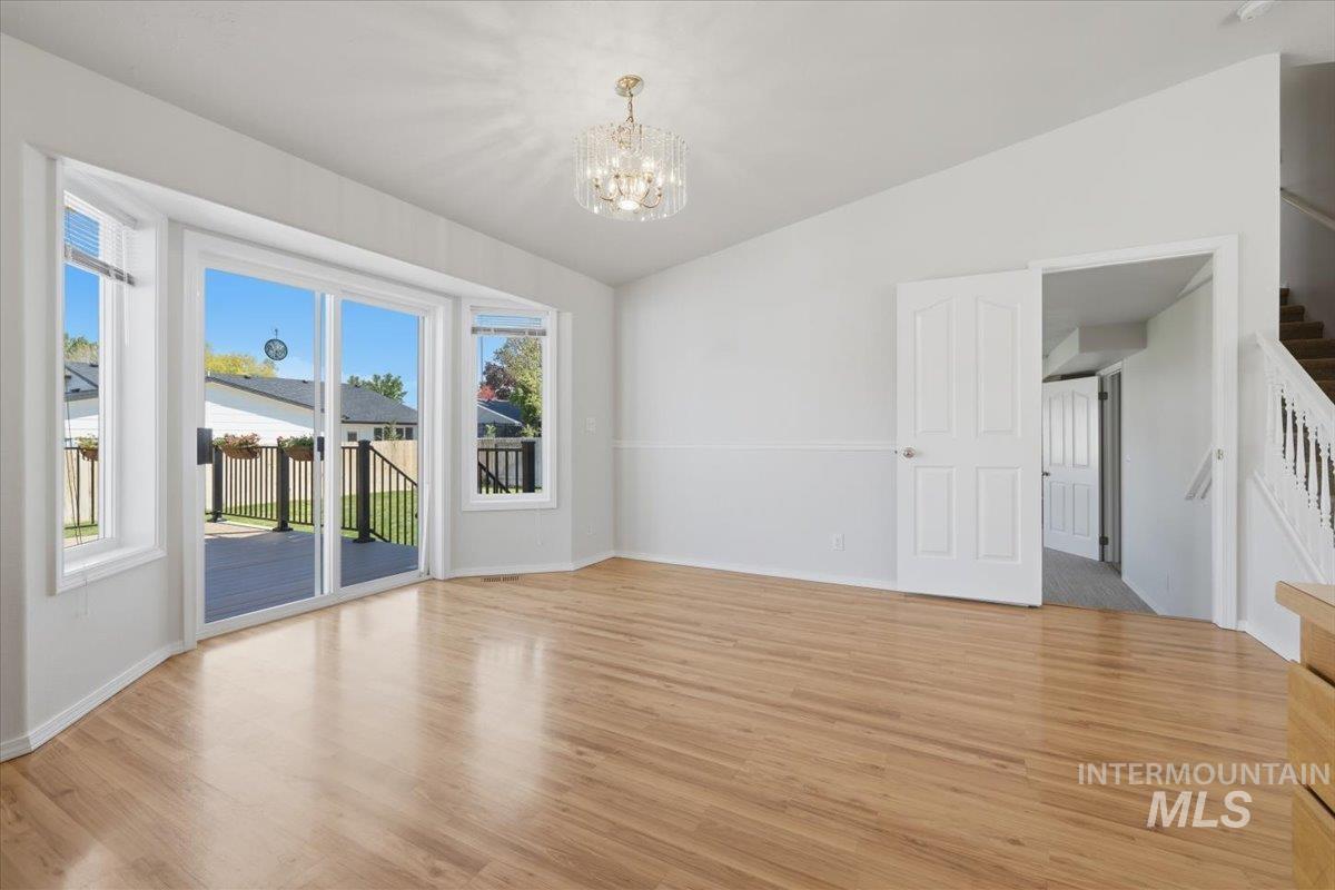 1128 West State Street Meridian, ID 83642 - Photo 15 of 50 Spacious interior featuring wood-finish flooring, white walls, and a crystal chandelier