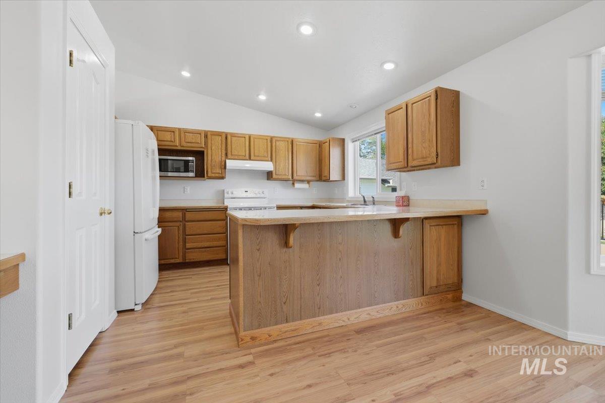 1128 West State Street Meridian, ID 83642 - Photo 17 of 50 Kitchen featuring wood-finish flooring, vaulted ceilings, recessed lighting, wood cabinetry, and a peninsula with countertop seating