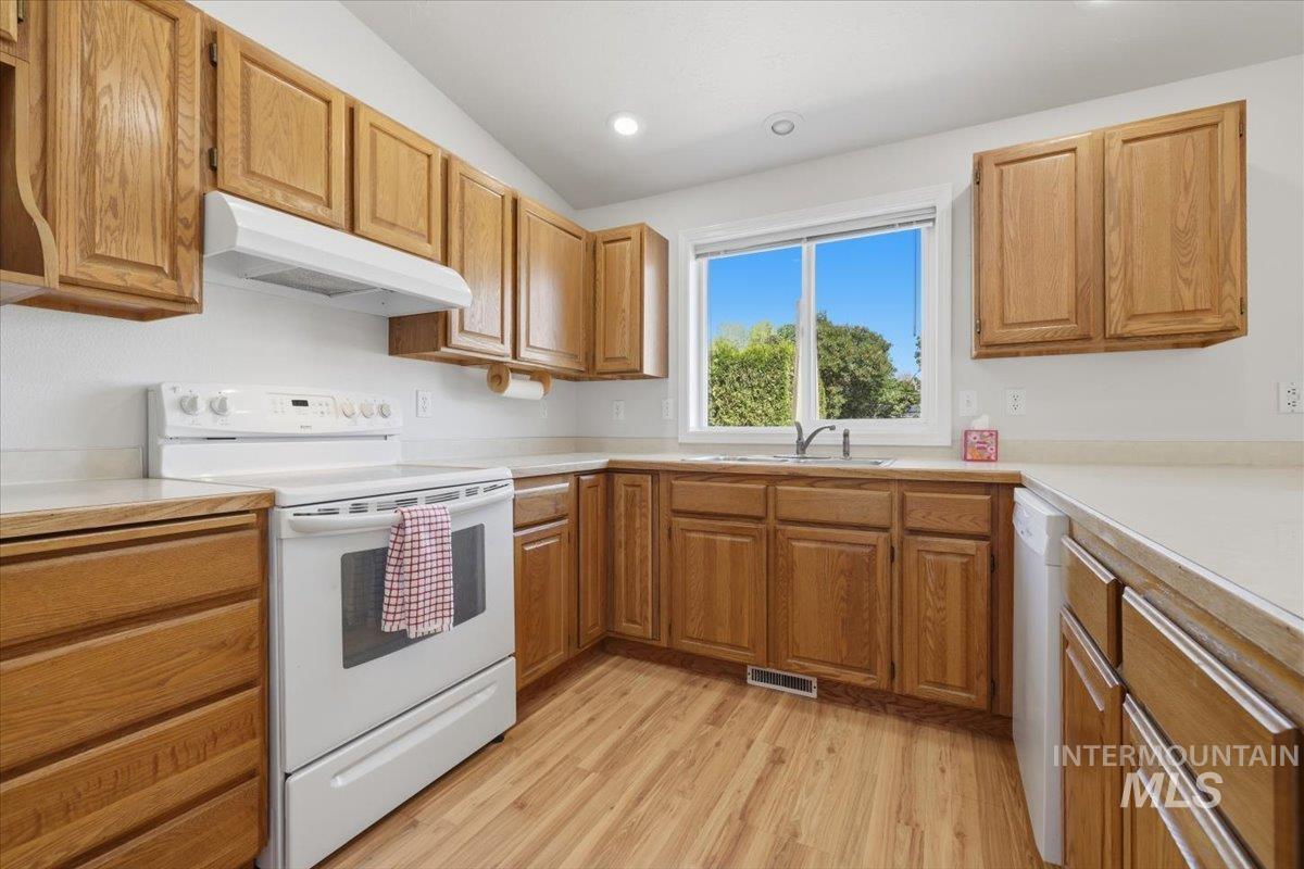 1128 West State Street Meridian, ID 83642 - Photo 18 of 50 Kitchen featuring wood-finish flooring, light-toned countertops, wooden cabinetry, a stainless steel sink, and a large window