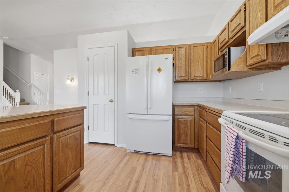 1128 West State Street Meridian, ID 83642 - Photo 20 of 50 Kitchen featuring wood-finish flooring, light wood cabinetry, white countertops, built-in microwave, and a white refrigerator