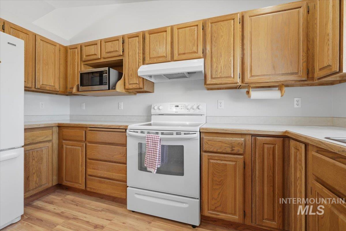1128 West State Street Meridian, ID 83642 - Photo 21 of 50 Kitchen featuring wood-finish cabinetry, white countertops, a white range, a built-in microwave, and wood-finish flooring