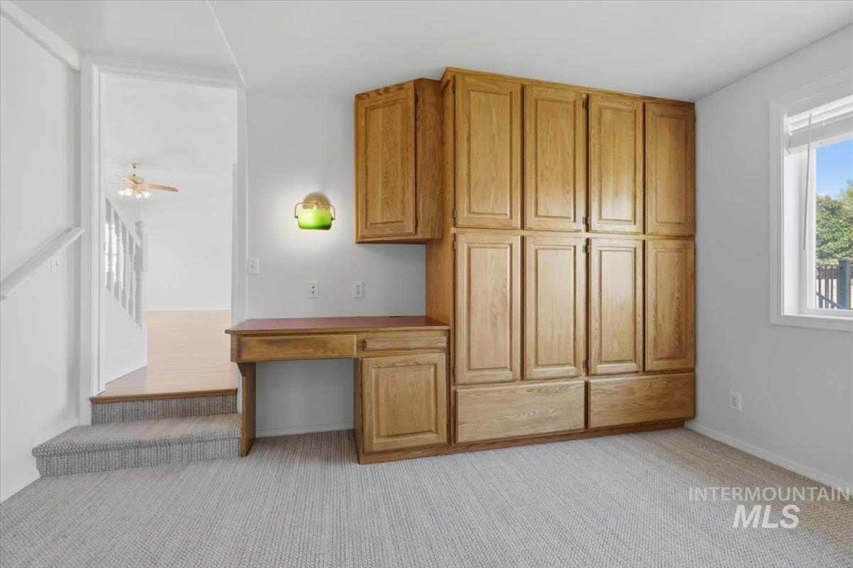 1128 West State Street Meridian, ID 83642 - Photo 23 of 50 Built-in wood cabinetry with a dedicated desk area, light gray carpet flooring, and a window with white blinds