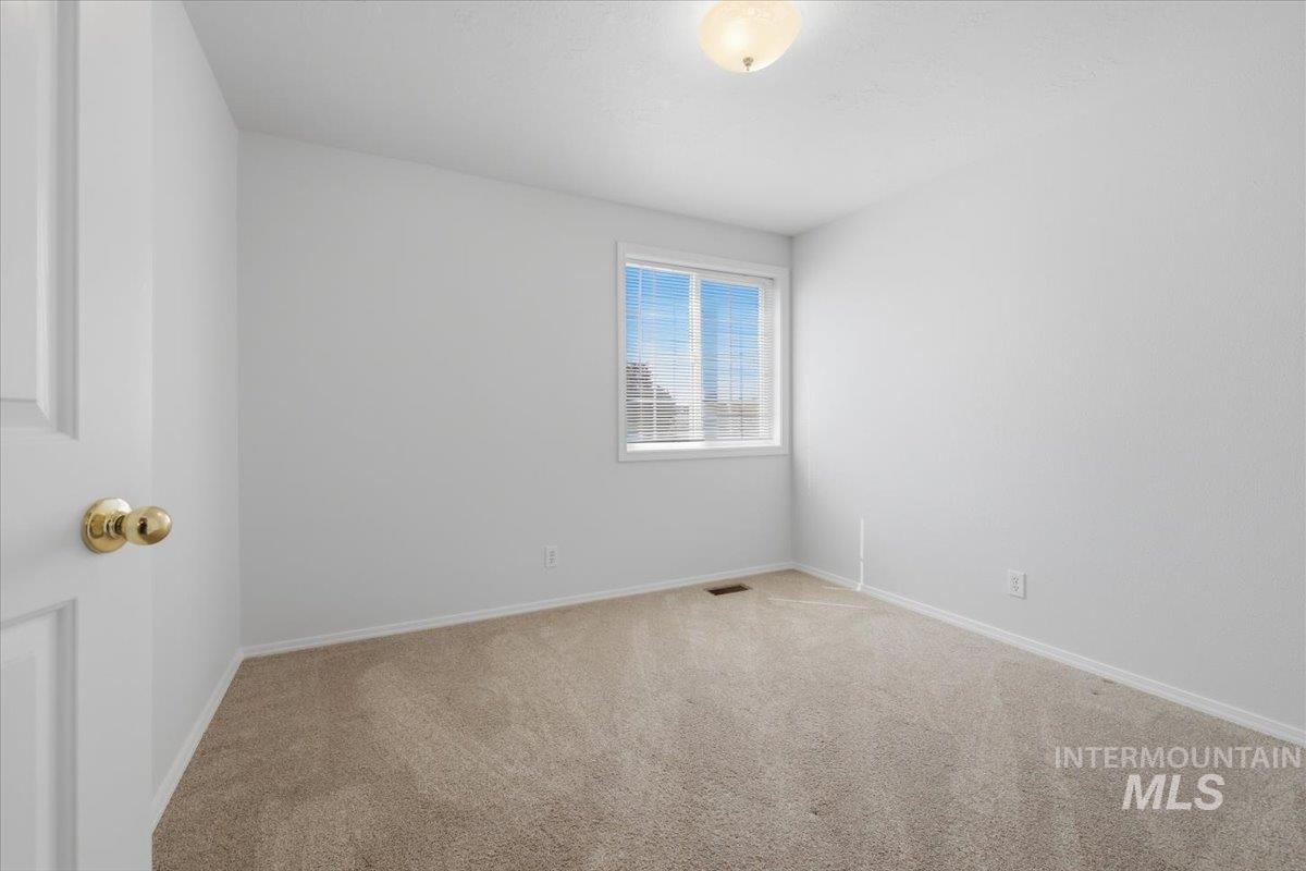 1128 West State Street Meridian, ID 83642 - Photo 35 of 50 Neutral-toned carpeted interior space featuring white walls and trim, a single window with blinds, and a flush mount ceiling light fixture