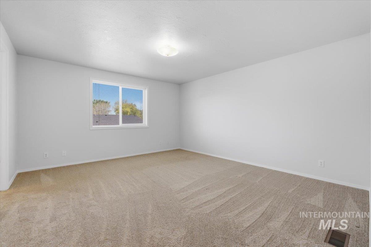 1128 West State Street Meridian, ID 83642 - Photo 39 of 50 Neutral-toned carpeting spans this spacious room, featuring a large window with white trim and a ceiling-mounted light fixture