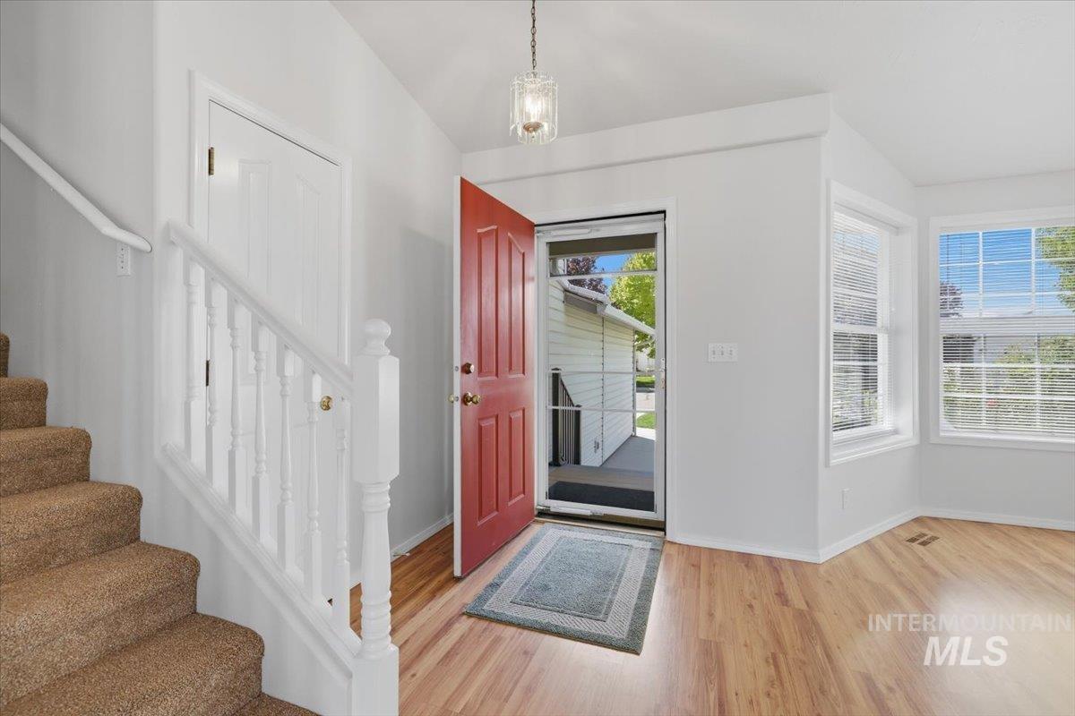 1128 West State Street Meridian, ID 83642 - Photo 6 of 50 Entryway featuring a bright red door, wood-finish flooring, and a carpeted staircase with white balusters