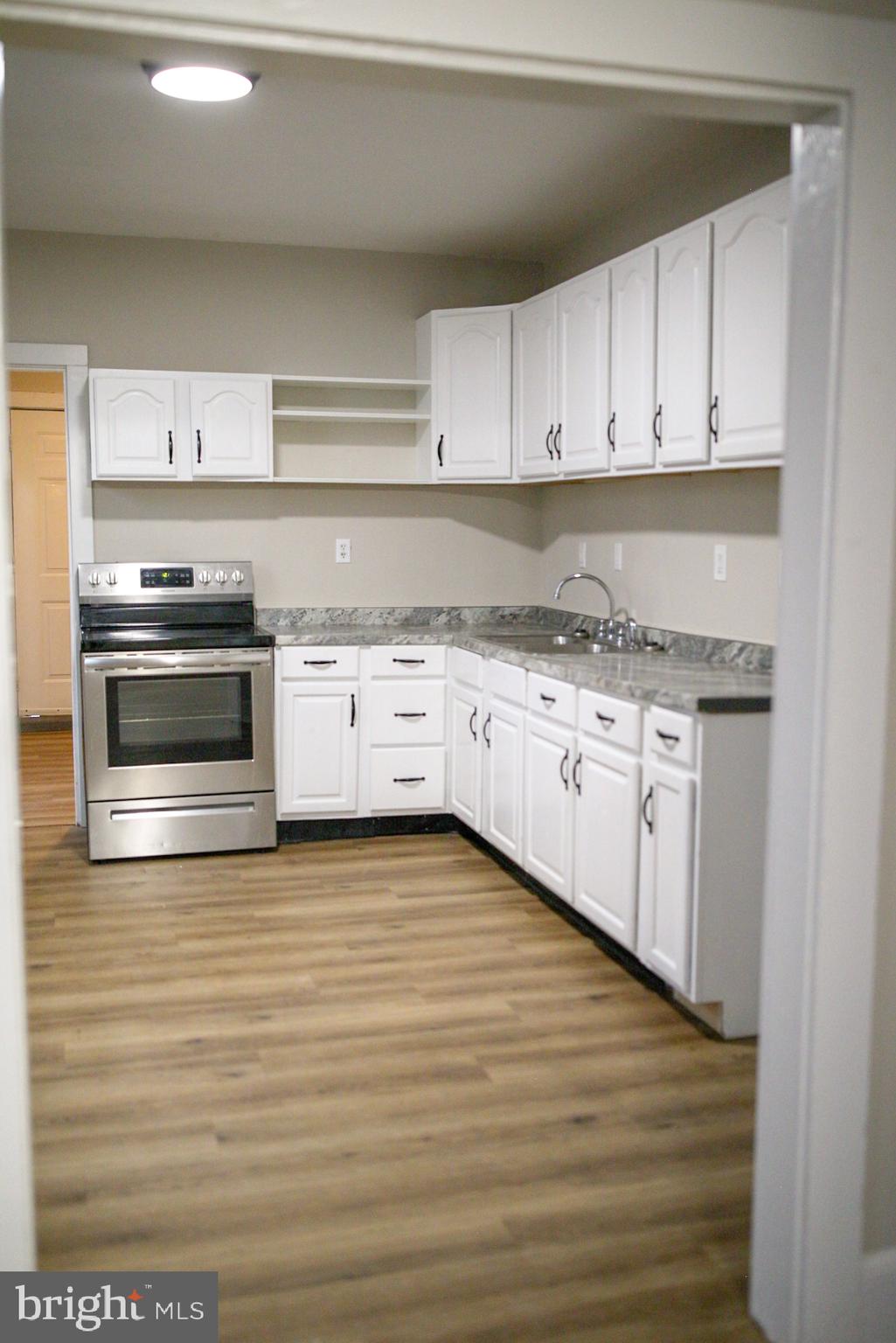 179 Main Street Hartly, DE 19953 - Photo 5 of 43 a kitchen with granite countertop a stove top oven a sink and cabinets