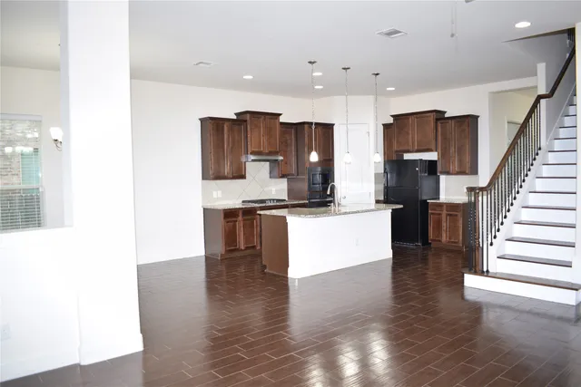 a large kitchen with stainless steel appliances kitchen island granite countertop a refrigerator and a stove top oven