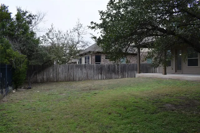 a view of a backyard with large trees and wooden fence
