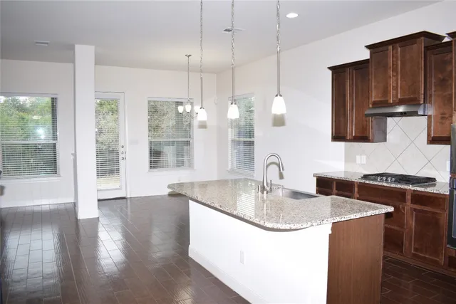 a kitchen with stainless steel appliances granite countertop a sink a stove and a wooden floors