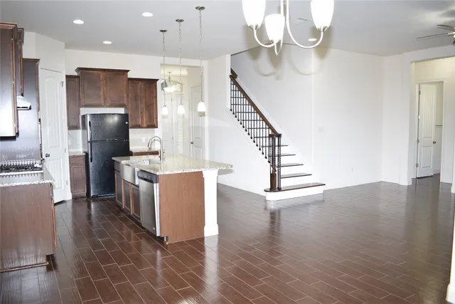 a kitchen with granite countertop a refrigerator a sink and a stove top oven