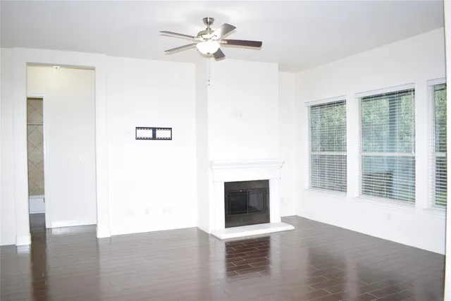 a view of a livingroom with a ceiling fan a fireplace and wooden floor