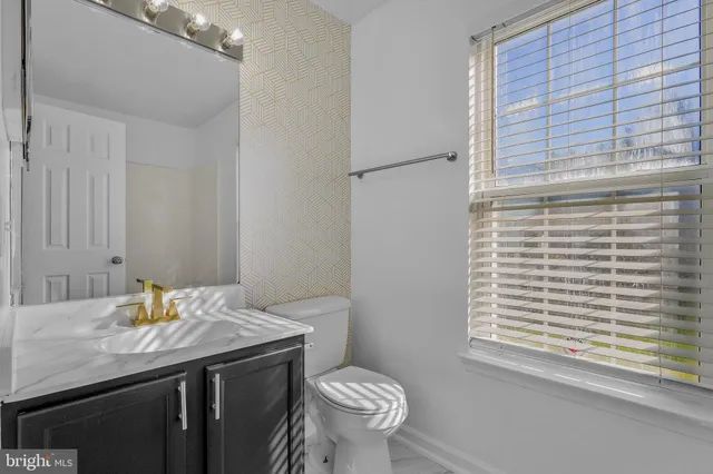 a bathroom with a granite countertop sink toilet and a mirror