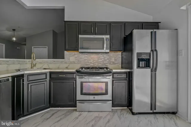 a kitchen with stainless steel appliances granite countertop a refrigerator stove and sink