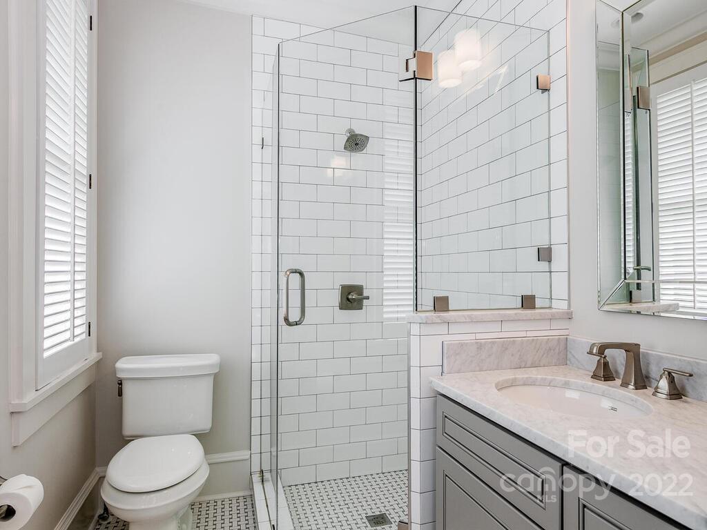 1210 Dilworth Road Charlotte, NC 28203 - Photo 23 of 39 a bathroom with a granite countertop toilet a sink a mirror and shower